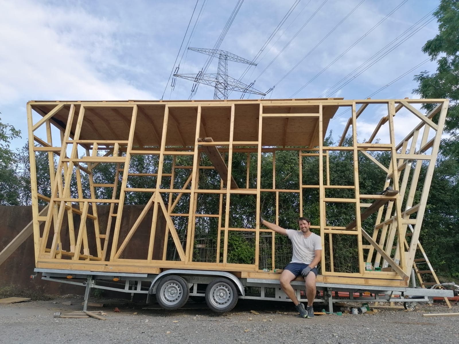 Ich sitze vor dem Holzrahmen unseres Tiny Hauses auf dem Anhänger